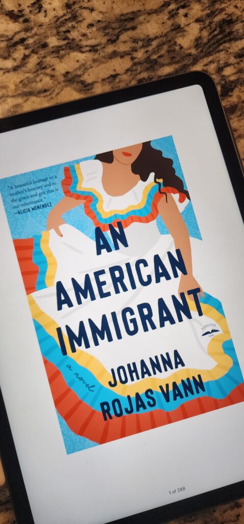 iPad with cover of book, there is a woman with a white, yellow, blue and dress and the words an american immigrant Johanna Rojas Vann across.